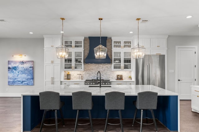 10411 E Rio Grande River Dr, Cypress, TX 77433 - kitchen featuring freestanding refrigerator, custom exhaust hood, recessed lighting, tasteful backsplash, and a spacious island