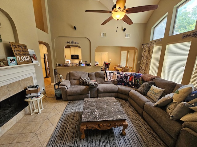 21235 Pennshore Ln, Katy, TX 77450 - living room featuring high vaulted ceiling, arched walkways, light tile patterned floors, a ceiling fan, and a tile fireplace