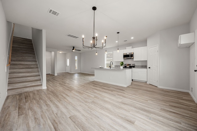 8 Donna Ct, Brookshire, TX 77423 - unfurnished living room with a sink, a chandelier, light wood-style flooring, baseboards, and stairs
