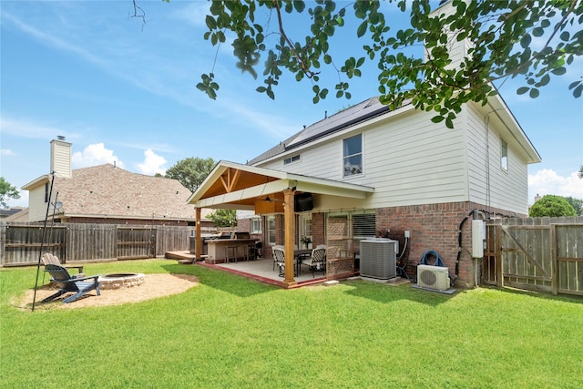 6923 Cobblestone Path, Houston, TX 77084 - rear view of property featuring a fire pit, central AC, brick siding, a patio area, and roof mounted solar panels