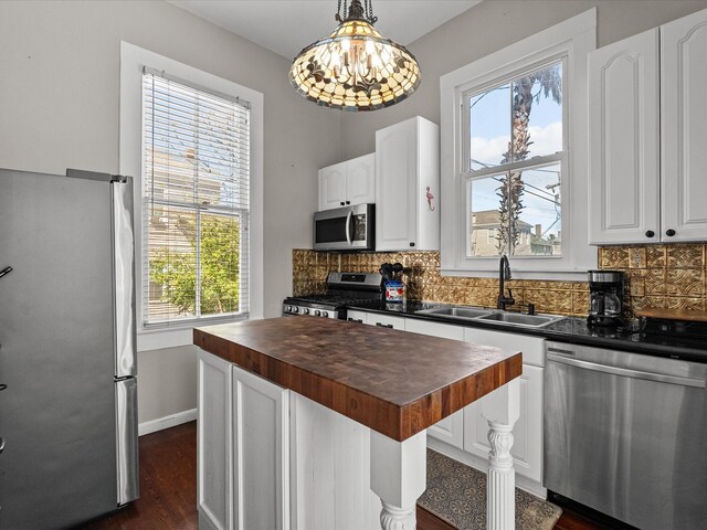 1014 20th St, Galveston, TX 77550 - kitchen with butcher block countertops, stainless steel appliances, a sink, a kitchen island, and decorative backsplash