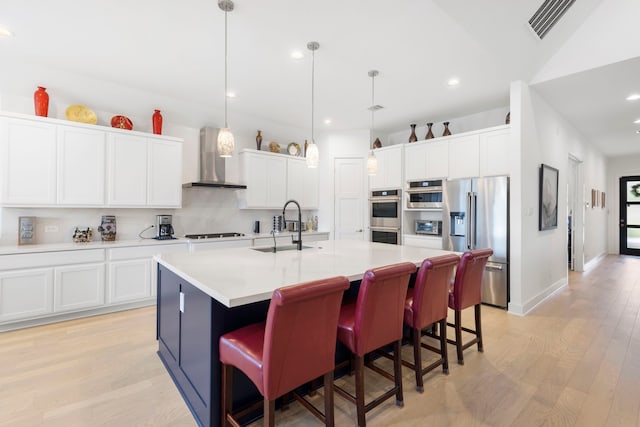 12211 Grey Plover Ct, Conroe, TX 77304 - kitchen with stainless steel appliances, wall chimney range hood, light wood finished floors, light countertops, and recessed lighting