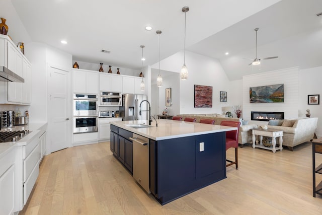 12211 Grey Plover Ct, Conroe, TX 77304 - kitchen with stainless steel appliances, light wood-style flooring, white cabinetry, a kitchen breakfast bar, and light countertops