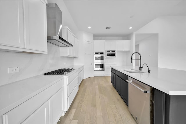 12211 Grey Plover Ct, Conroe, TX 77304 - kitchen with appliances with stainless steel finishes, wall chimney exhaust hood, white cabinets, light wood-style flooring, and dark cabinets