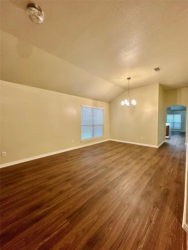 5642 Park Village Dr, Houston, TX 77048 - spare room featuring lofted ceiling, dark wood finished floors, a textured ceiling, a chandelier, and arched walkways