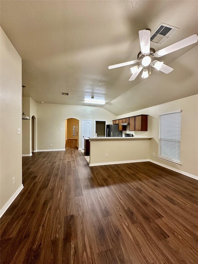 5642 Park Village Dr, Houston, TX 77048 - unfurnished living room featuring arched walkways, a ceiling fan, baseboards, vaulted ceiling, and dark wood-style floors