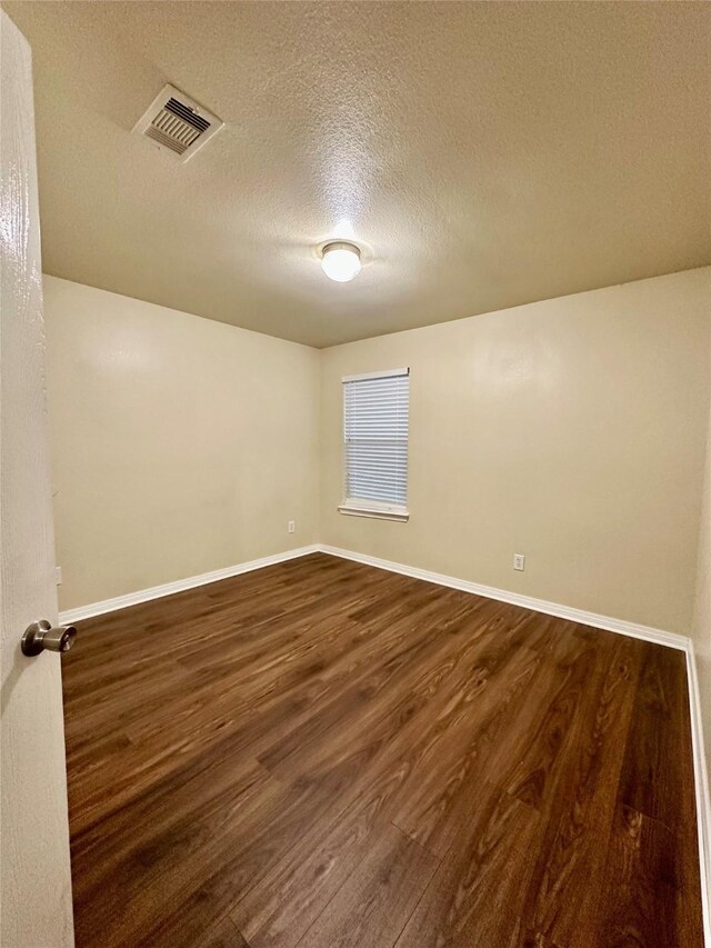 5642 Park Village Dr, Houston, TX 77048 - unfurnished room with dark wood-style flooring, a textured ceiling, and baseboards