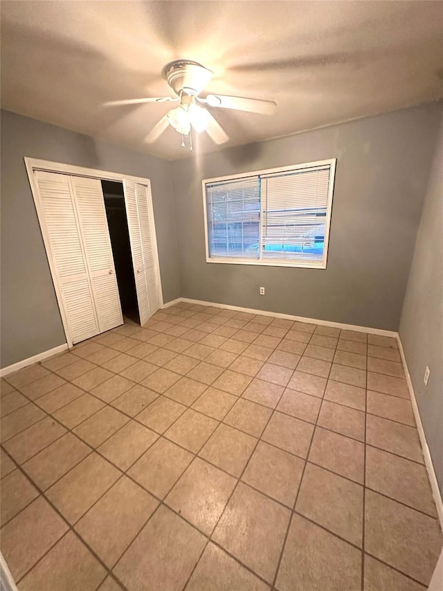 3918 Dalmatian Dr, Houston, TX 77045 - unfurnished bedroom with light tile patterned floors, a closet, a ceiling fan, and baseboards