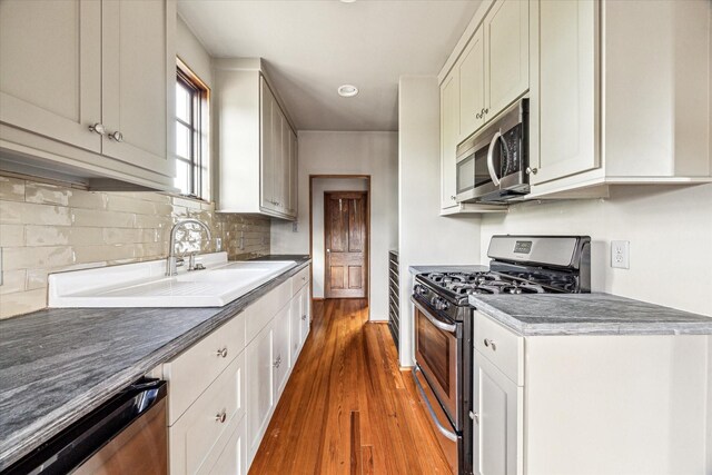 808 Coronado St, Houston, TX 77009 - kitchen with stainless steel appliances, dark wood-style flooring, a sink, decorative backsplash, and recessed lighting
