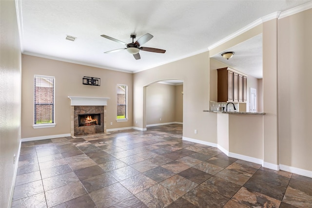 1511 Tournament Ct, Crosby, TX 77532 - unfurnished living room with baseboards, stone tile flooring, a ceiling fan, arched walkways, and ornamental molding