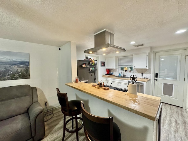 11837 13th St, Santa Fe, TX 77510 - kitchen featuring light wood-style floors, butcher block countertops, a textured ceiling, white cabinets, and freestanding refrigerator