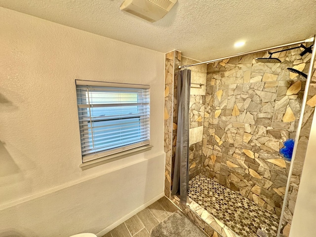 11837 13th St, Santa Fe, TX 77510 - bathroom with tiled shower, a textured ceiling, wood finished floors, baseboards, and toilet