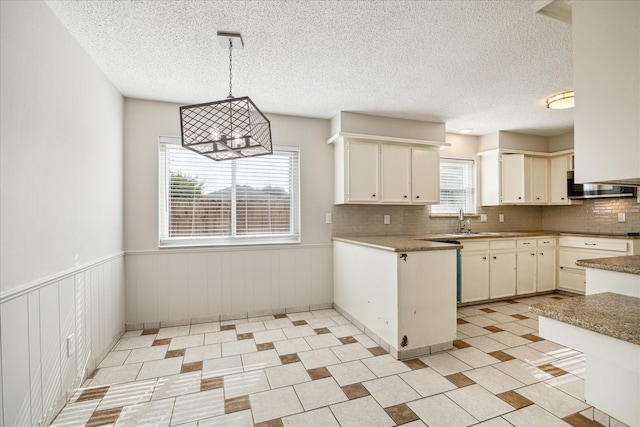 13603 Woodchester Dr, Sugar Land, TX 77498 - kitchen with stainless steel microwave, a textured ceiling, tasteful backsplash, pendant lighting, and a wainscoted wall