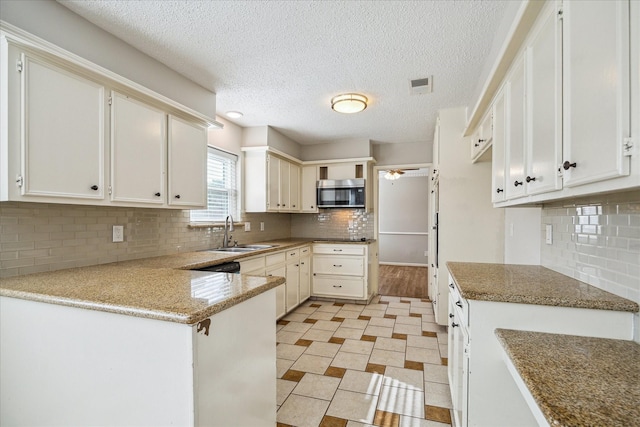 13603 Woodchester Dr, Sugar Land, TX 77498 - kitchen featuring stainless steel microwave, a peninsula, decorative backsplash, a ceiling fan, and a textured ceiling