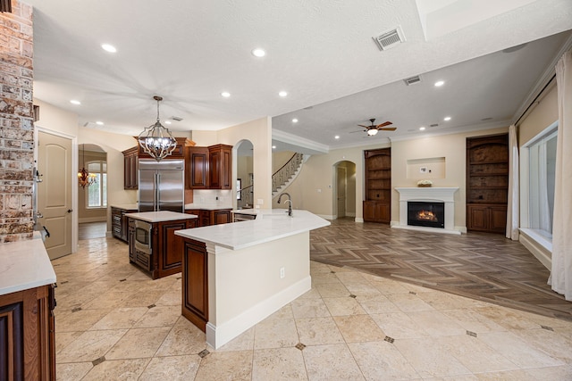 24914 Misty Heath Ln, Katy, TX 77494 - kitchen featuring arched walkways, built in fridge, a sink, an island with sink, and recessed lighting