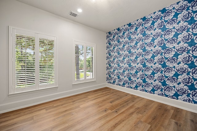 24914 Misty Heath Ln, Katy, TX 77494 - spare room with wallpapered walls, baseboards, light wood-type flooring, and a textured ceiling