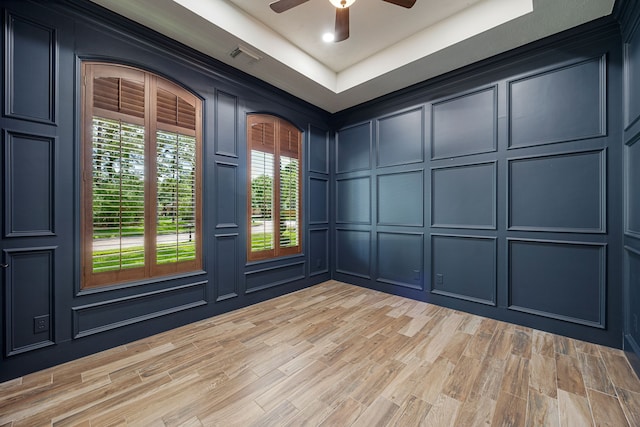 24914 Misty Heath Ln, Katy, TX 77494 - empty room featuring a decorative wall, ceiling fan, light wood-style flooring, and a raised ceiling