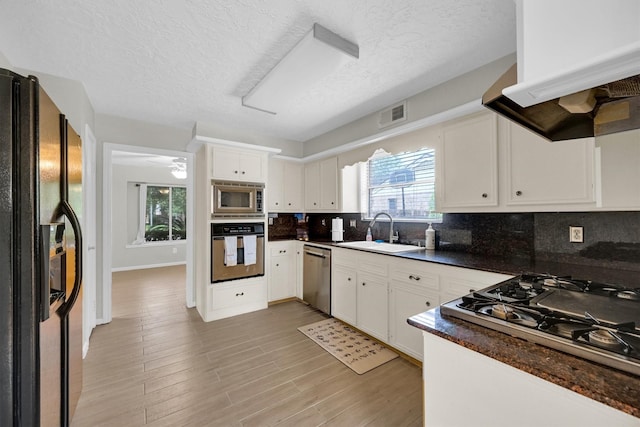 6606 Chancellor Dr, Spring, TX 77379 - kitchen with appliances with stainless steel finishes, a sink, premium range hood, decorative backsplash, and a textured ceiling