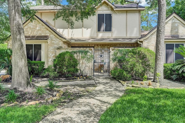 6606 Chancellor Dr, Spring, TX 77379 - tudor house with stucco siding, a gate, a shingled roof, and brick siding