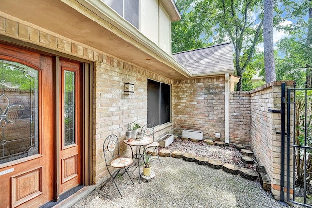 6606 Chancellor Dr, Spring, TX 77379 - view of exterior entry with a gate, a shingled roof, and brick siding