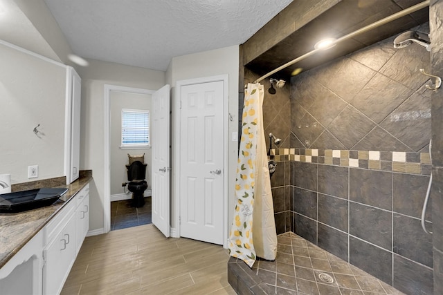 6606 Chancellor Dr, Spring, TX 77379 - bathroom with tiled shower, vanity, wood finished floors, and baseboards