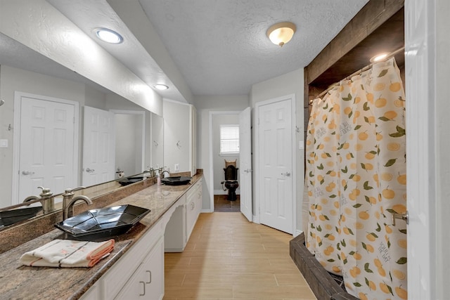 6606 Chancellor Dr, Spring, TX 77379 - full bathroom with double vanity, curtained shower, wood finished floors, a textured ceiling, and baseboards
