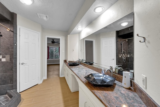 6606 Chancellor Dr, Spring, TX 77379 - bathroom featuring a stall shower, double vanity, wood finished floors, a textured ceiling, and baseboards