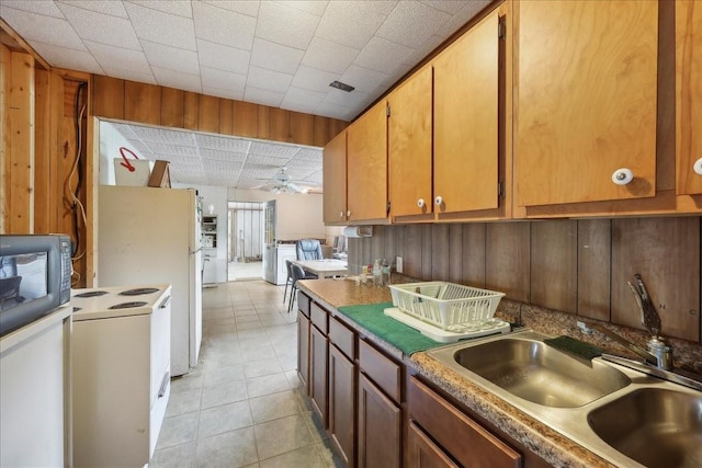 2432 Westpine Rd, Beaumont, TX 77713 - kitchen with a sink, light tile patterned floors, a ceiling fan, electric stove, and wooden walls