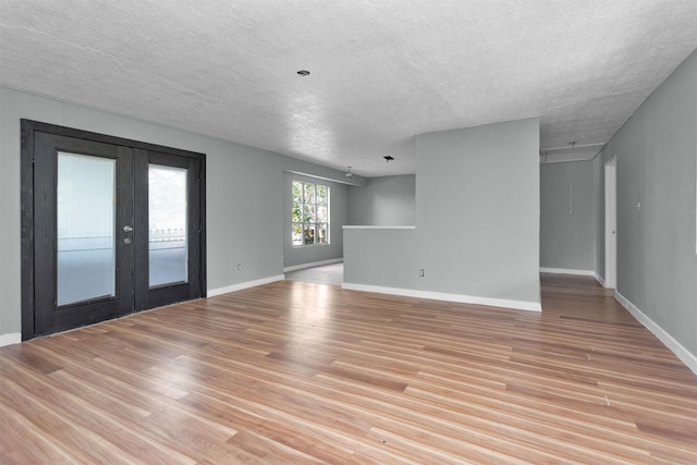 4909 Falls St, Houston, TX 77026 - unfurnished room featuring a textured ceiling, light wood finished floors, french doors, and baseboards