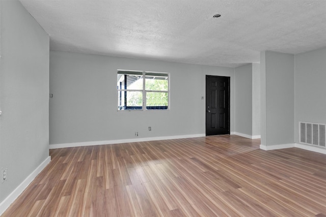 4909 Falls St, Houston, TX 77026 - empty room featuring a textured ceiling, light wood finished floors, and baseboards