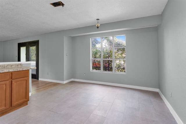 4909 Falls St, Houston, TX 77026 - unfurnished dining area featuring plenty of natural light, a textured ceiling, baseboards, and light tile patterned flooring