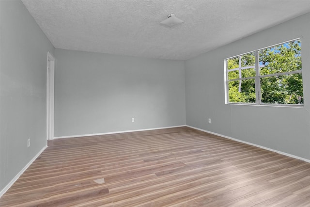 4909 Falls St, Houston, TX 77026 - spare room with a textured ceiling, light wood-style floors, and baseboards