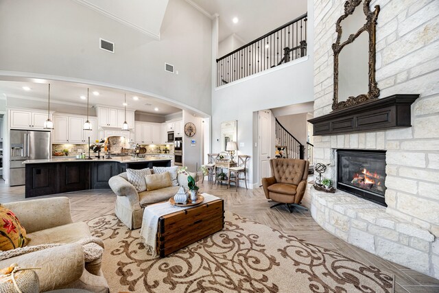 1003 Angel Forest Ct, Pinehurst, TX 77362 - living area with ornamental molding, a high ceiling, a stone fireplace, stairs, and arched walkways