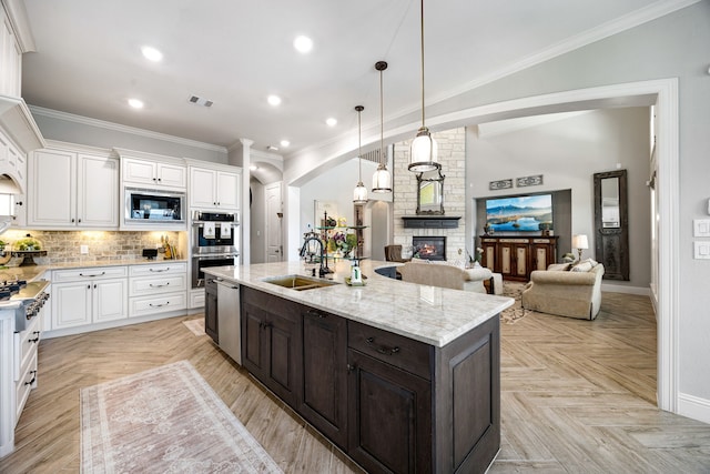 1003 Angel Forest Ct, Pinehurst, TX 77362 - kitchen featuring appliances with stainless steel finishes, white cabinetry, arched walkways, dark brown cabinets, and an island with sink