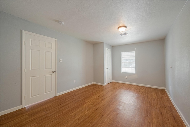 5619 Willow Glen Dr, Houston, TX 77033 - empty room featuring light wood finished floors, a textured ceiling, baseboards, and a smoke detector