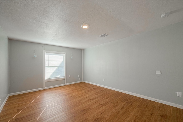 5619 Willow Glen Dr, Houston, TX 77033 - empty room featuring light wood-style floors, a textured ceiling, a smoke detector, and baseboards