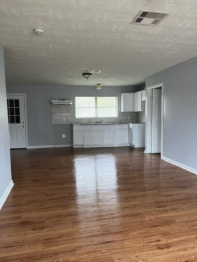 6058 Glenhurst Dr, Houston, TX 77033 - unfurnished living room featuring a textured ceiling, dark wood-type flooring, and baseboards