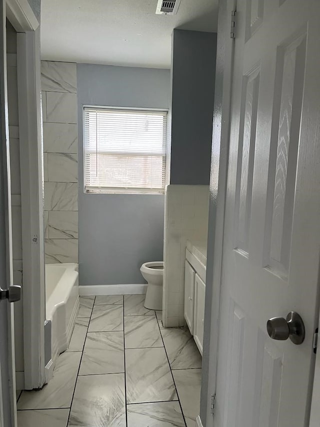 6058 Glenhurst Dr, Houston, TX 77033 - full bath featuring marble look tiles, toilet, vanity, and baseboards