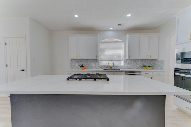 16411 Jadestone Terrace Ln, Houston, TX 77044 - kitchen with a sink, appliances with stainless steel finishes, backsplash, white cabinetry, and recessed lighting