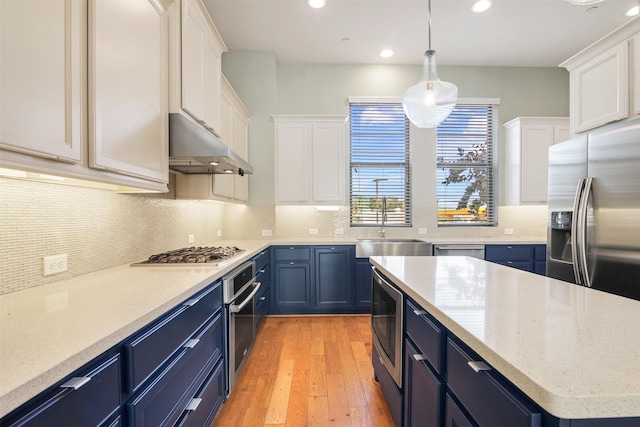 5421 Larkin St, Houston, TX 77007 - kitchen featuring blue cabinets, under cabinet range hood, appliances with stainless steel finishes, recessed lighting, and light wood-style floors