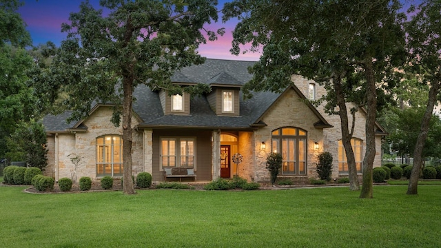 28622 Champions Dr, Magnolia, TX 77355 - french country inspired facade featuring stone siding, a front yard, a shingled roof, and covered porch