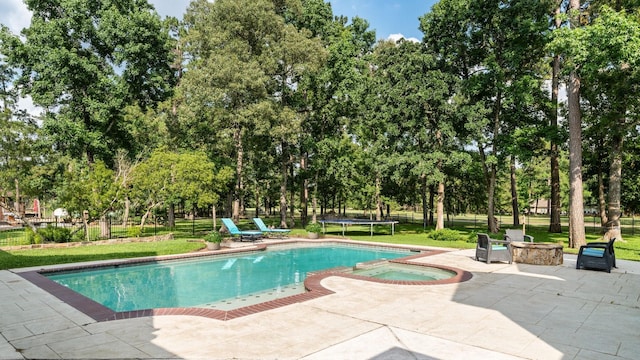 28622 Champions Dr, Magnolia, TX 77355 - view of swimming pool featuring a patio, view of wooded area, a pool with connected hot tub, and a trampoline