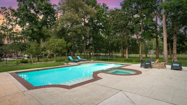 28622 Champions Dr, Magnolia, TX 77355 - pool at dusk featuring a patio area, a pool with connected hot tub, view of wooded area, and a trampoline