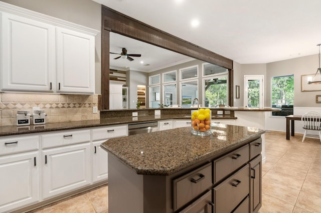 28622 Champions Dr, Magnolia, TX 77355 - kitchen with stainless steel dishwasher, a kitchen island, dark stone counters, backsplash, and light tile patterned floors