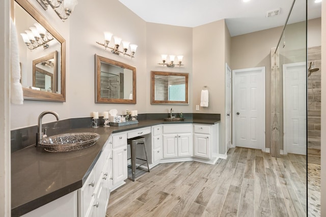 28622 Champions Dr, Magnolia, TX 77355 - bathroom with double vanity, a tile shower, wood finished floors, and a chandelier