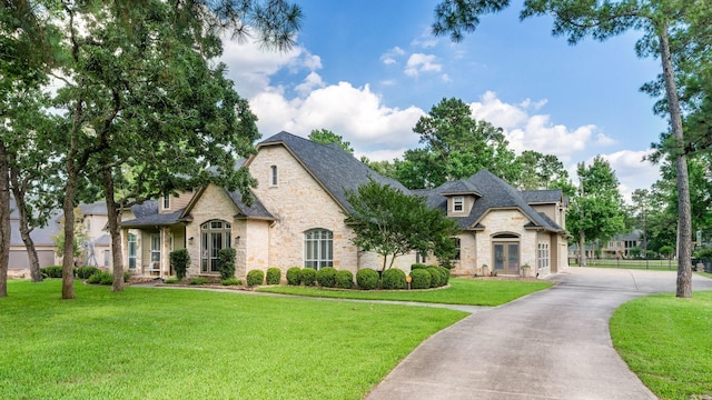 28622 Champions Dr, Magnolia, TX 77355 - french country home with stone siding, a front yard, and driveway