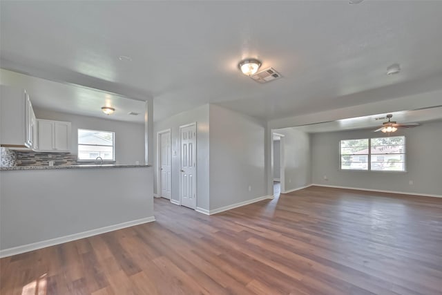 3918 Tavenor Ln, Houston, TX 77047 - unfurnished living room with dark wood-style flooring, a ceiling fan, baseboards, and a sink