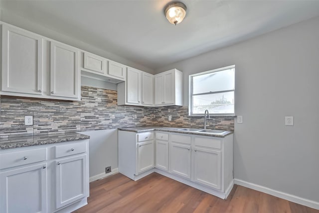 3918 Tavenor Ln, Houston, TX 77047 - kitchen featuring a sink, tasteful backsplash, dark wood finished floors, white cabinetry, and baseboards