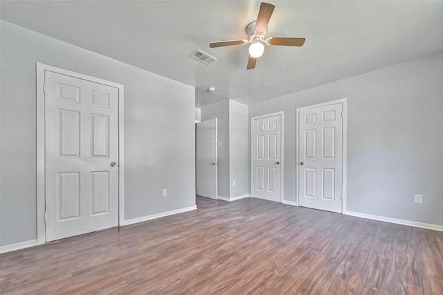 3918 Tavenor Ln, Houston, TX 77047 - unfurnished bedroom with dark wood-type flooring, baseboards, multiple closets, and a ceiling fan