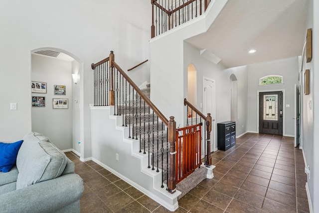 6546 Turner Fields Ln, Dickinson, TX 77539 - entryway with arched walkways, a towering ceiling, dark tile patterned flooring, stairs, and baseboards